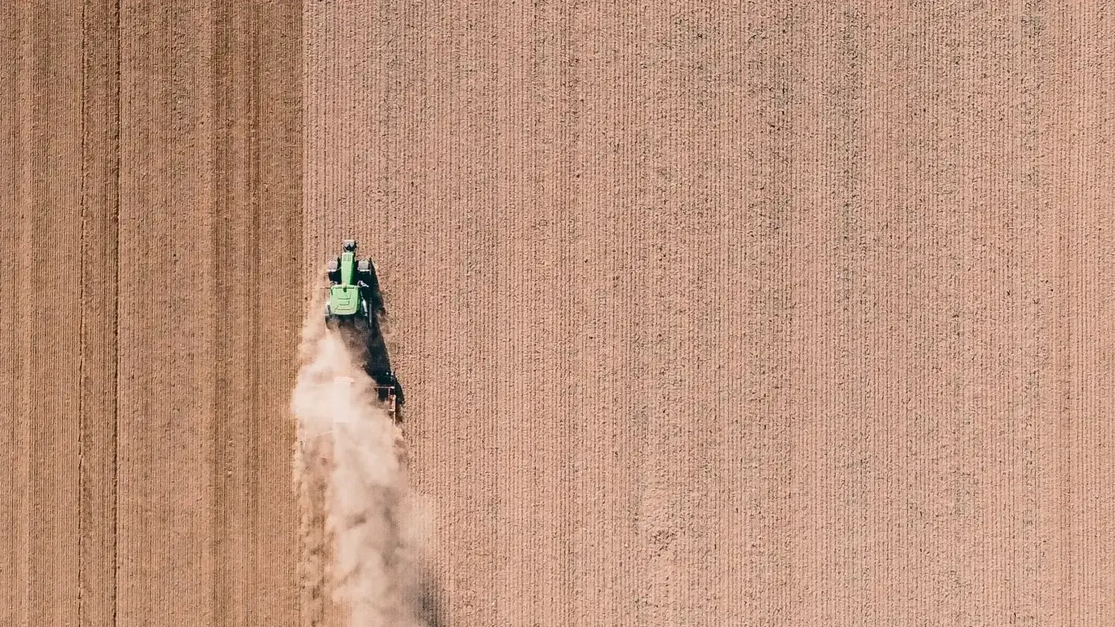 Tracteur labourant un champ vu du ciel, illustration des solutions de financement FOUNDY pour les agriculteurs